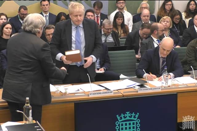 The Clerk to the Committee (left) administers the oath to former prime minister Boris Johnson ahead of his evidence to the Privileges Committee at the House of Commons, London