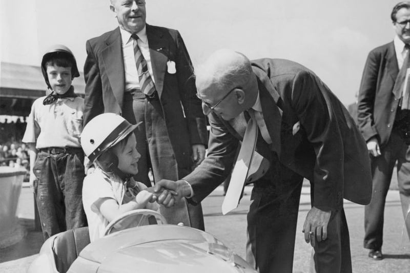 Sir Leonard Lord (1896 - 1967), chairman of the Austin Motor Company, congratulates 8-year-old Alan Swadling on winning the Junior Grand Prix, a race for children of employees at Longbridge, 10th July 1955. The company is celebrating its Golden Jubilee (50 years), and Alan’s prize is the car he is driving.  (Photo by J. Wilds/Keystone/Hulton Archive/Getty Images)