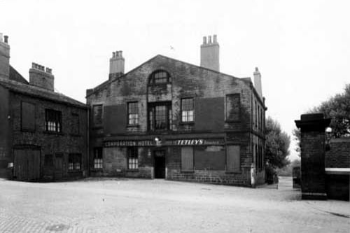 The rear of the Corporation Hotel, formerly Campfield House at number 4A Camp Road. The hotel and the building next door both have bricked up windows. Iron gates are on the right and a cobbled yard is in the foreground. Pictured in May 1950.
