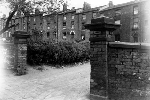 A view of houses taken from North Street in June 1950. The row of houses in the background are actually Brunswick Place. One can see the sign for 'Silverman & Son, wholesale drapers at number 5 Brunswick Place. There is a stone wall and gateposts in the foreground. Written on the left gatepost is Brunswick Place, with an arrow underneath pointing to the houses in the background. Next to this gatepost is a street sign for Brunswick Street.