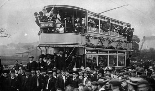 A large crowd is pictured gathered around a tram, the first on the route out to Yeadon in May 1909. .Initially the tram line went only as far as Green Lane, to the south of the town, before being extended to White Cross, Guiseley, later the same year.