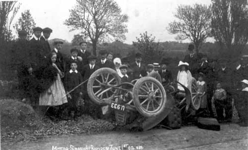  Postcard from June 1909 with 'Motor Car smash at Rawdon' on it. Group of people in the background, wearing clothes typical of the period.