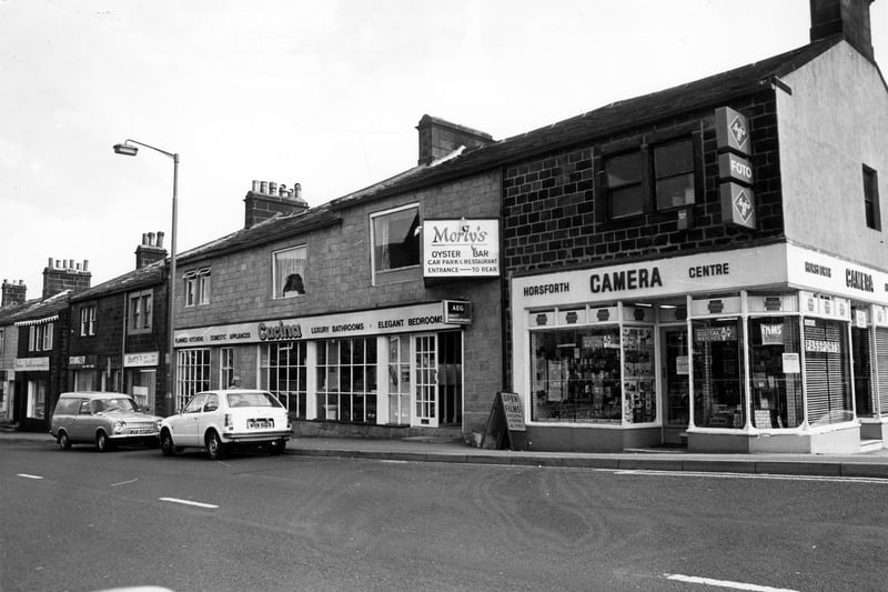 New Road Side pictured in June 1980.Pictured, far left, is Barbara Smith, Soft Furnishings at 135, then Ronald Stankler Tailoring at 137, Barry's Hair Fashions at 139, Cucina occupying 141 to 143 with sign for Morly's Oyster Bar above, and Horsforth Camera Centre at number 145. The Camera Centre is at the junction with Victoria Gardens, right.