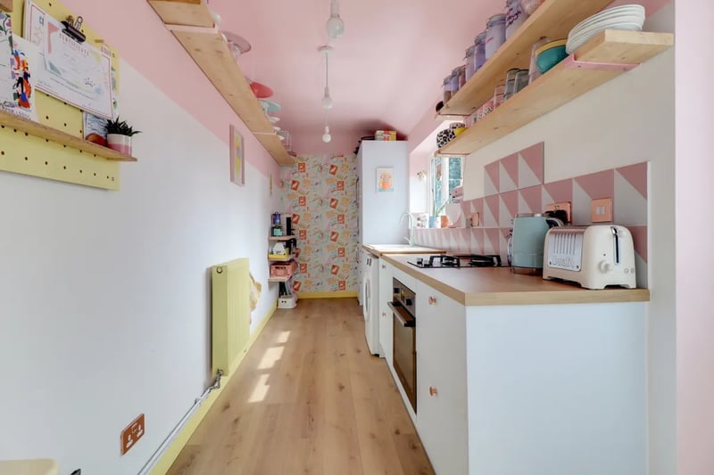 The galley-style kitchen, off to the rear of the property, is fitted with a contemporary range of white units and an integrated oven and hob