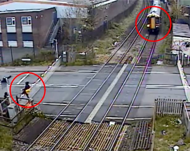 Man climbs train crossing barrier and strolls across tracks moments before a high speed train travels through at Station Road in Langley Green, Oldbury, West Midlands, on April 27, 2024.