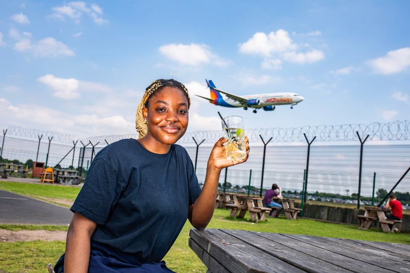 Geraldine Osamogie, 20, from Manchester, enjoying a drink as a plane passes by. 