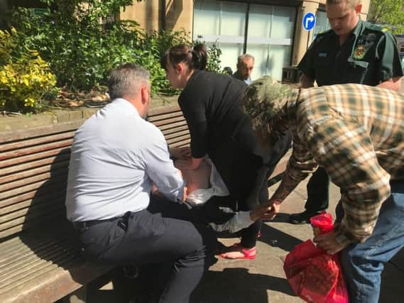 Laura, dressed in black, and the retired police officer, in shirt and trousers, help the man.