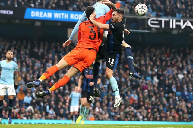 Manchester City goalkeeper Ederson (left) punches clear ahead of John Stones (top) and Rotherham United's Jon Taylor during the Emirates FA Cup, third round match at the Eithad Stadium, Manchester.Martin Rickett/PA Wire.