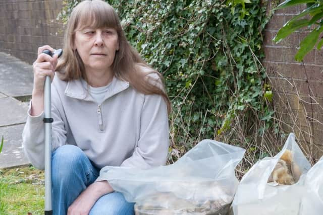 Partially sighted Gillian Thorpe with the remnants of her kitchen ceiling which fell on them after a water leak in the roof