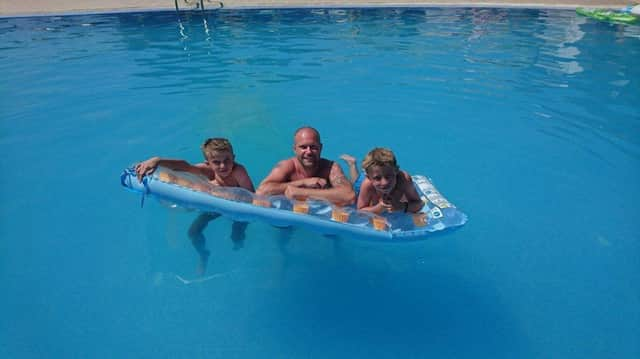 Hero police officer Dan Radford has been hailed a hero after saving a young boy from drowing while on holiday in Kos, Greece. Pictured with sons Alex and Lukas