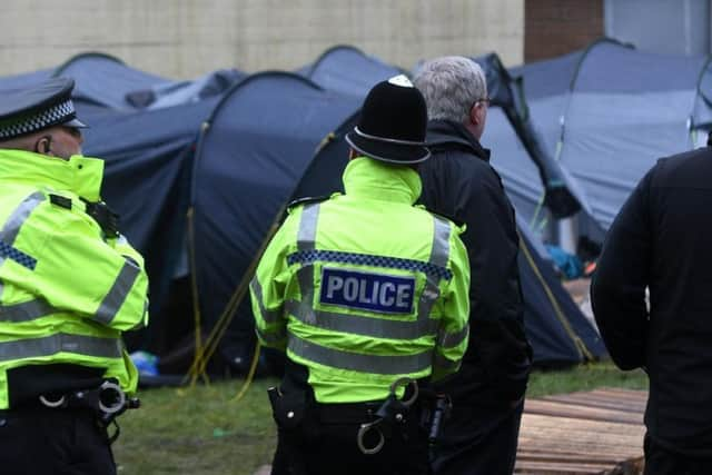 Police and council workers look on.