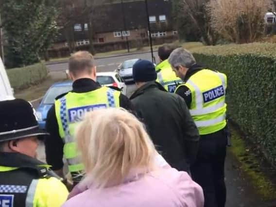 Police officers lead the arrested man away.